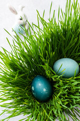Colorful Easter eggs in the grass and cute bunnies, searching for eggs on Easter day, top view, copy space