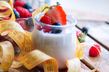 Jars of fresh yogurt, berries, blueberries, strawberries and measuring tape, diet concept