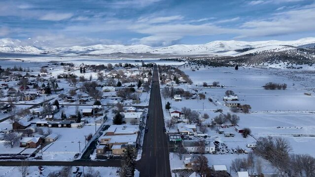 Aerial winter snow valley rural town main Street fast mo. Aerial farming community agricultural economy. Homes and traffic on highway and Main Street. Mountain valley winter snow. Seasonal snowy city.