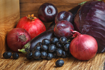Group of fruits and vegetables of red and purple hues on a wooden background. Fresh vegetables and fruits. Close-up.