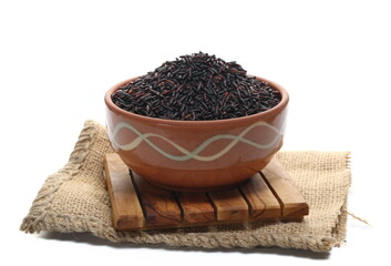Black rice uncooked in clay pot isolated on white