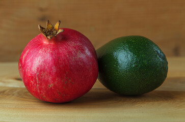 Red pomegranate and Green mango over a wooden background. Contrast of red and green colors. Fresh vegetables and fruits.