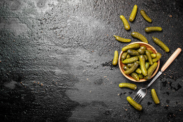 Wooden plate with pickles. On a black background.