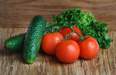 A few red tomatoes and cucumbers over a wooden background. Fresh vegetables.