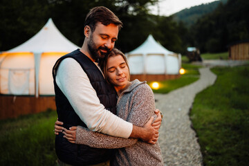 Beautiful couple embracing while standing near camp in mountains