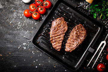 Grilled steak in a frying pan with tomatoes and spices.