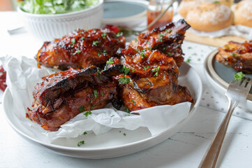 Oven baked thick pork ribs with homemade barbecue sauce, salad and bread for dinner or lunch on a table