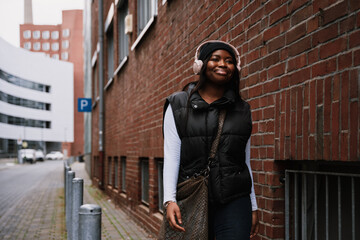 Cheerful african woman walking outdoors through city street