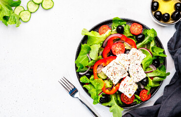 Greek salad with feta cheese, black olives, tomatoes, paprika, cucumber and red onion, healthy vegetarian mediterranean diet food. White background, top view