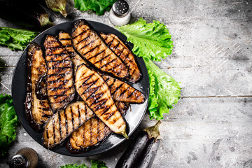 Grilled pieces of eggplant on a plate of lettuce. 