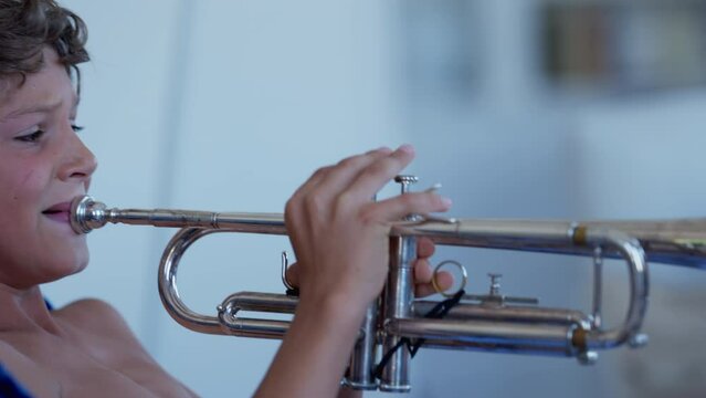 Creative child playing trumpet indoors. Little boy practicing musical instrument