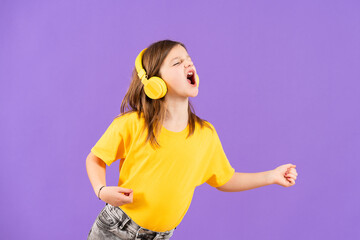 Cute little girl listening to music and singing out loud isolated on purple background