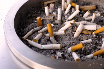 Cigarettes and ash on dirty sand in trash tray