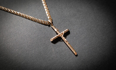 Golden cross necklace on the black background.