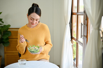 Beautiful Asian woman enjoys eating salad vegetables mix for her breakfast