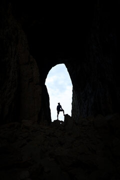 Silhouette of a man standing in a big hole through a famous mountain in Norway