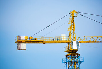 Load-lifting crane on a construction site against the blue sky. A group of lifting platforms for...