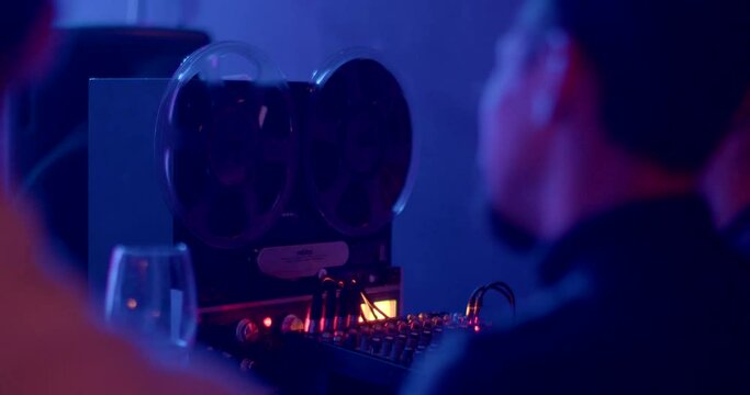 Babin movement on an analog tape recorder at a concert. Recording sound on old media to create sound recording effects. Mixer knobs in the light. CZ, Prague, Zizkov, 10.12.22.