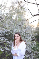 beautiful girl in a white shirt near a blooming tree. Beautiful warm spring and blossoming trees