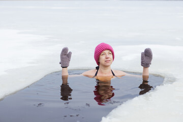 Winter swimming. Woman in frozen lake ice hole. Swimmers wellness and endorphin booster swim in...