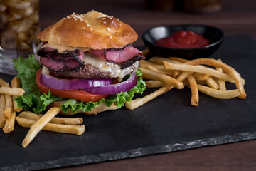 A juicy delicious burger made with a homemade ketogenic bun, served with fries.