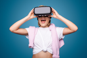 Young woman put on vr glasses enjoying an experiences of virtual world isolated over blue background. Attractive woman.