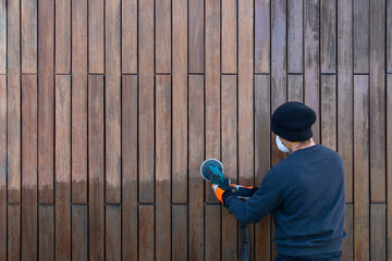 Sanding teak wood with orbital sander, professional renovation teak siding facade copy space