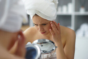 Young woman sits in the bathroom in front of the makeup mirror and does cosmetic procedures....