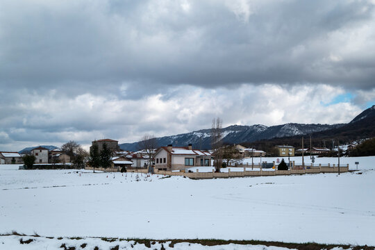 Pequena aldeia com montanhas ao fundo com um manto de neve num dia frio de inverno em Espanha