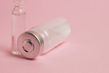 Ampoules with medicine or vitamins on pink paper background with copy space
