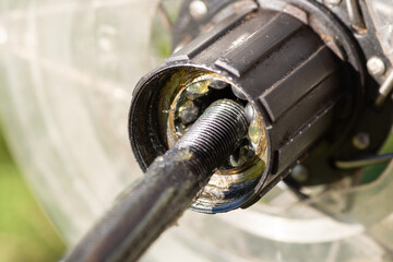 Bearings inside the bike hub, axle in the process of being installed in the hub. Bicycle service in warm sunny weather, new details, cleaning concept