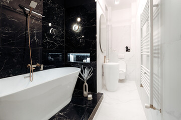 Spacious, fancy black and white marble bathroom with freestanding bathtub