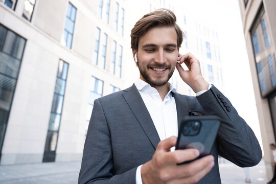 Confident young businessman using cell phone in the city.
