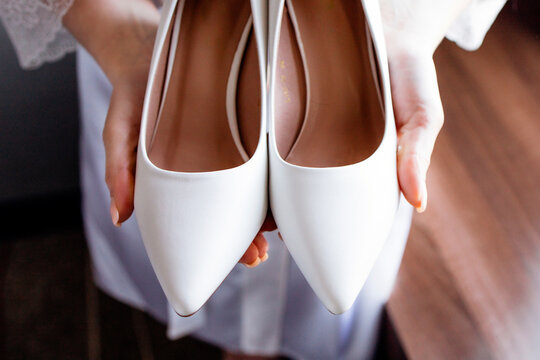 white wedding shoes without a heel in the hands of the bride
