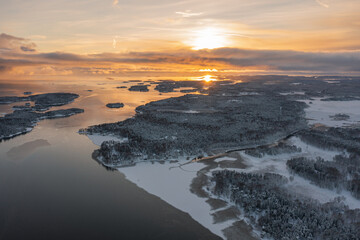 Top view of the snow-covered Soukka Islands in Espoo. Sunset on a winter day. There is ice on the water in places. Winter landscape. Scandinavia.