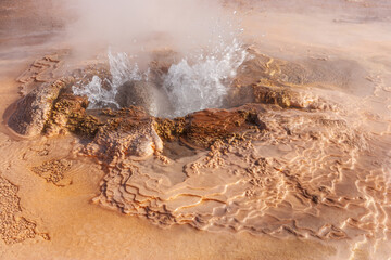 Hot spring with colored travertine deposits at the El Tatio geyser field in the high Andes of...