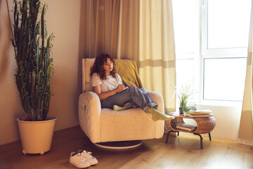 Cute girl in headphones sitting in the armchair with diary in hands
