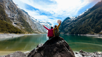  Travelers couple team look on the mountain landscape. Travel and active life concept  as Adventure travel in the mountains region in lake marian  fiordland national park - obrazy, fototapety, plakaty