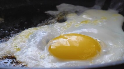 cracked egg sizzling in a frying pan.an egg being fried in a frying pan, scrambled eggs cooking. close-up, breakfast of fried eggs, selective focus.Eggs fried in a frying pan with hot steam.
