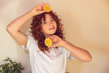 Curly-haired ginger girl with slices of orange in hands