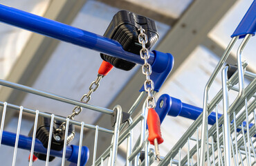 many trolley shopping cart with coin lock anti theft system outside in row sunny day different...