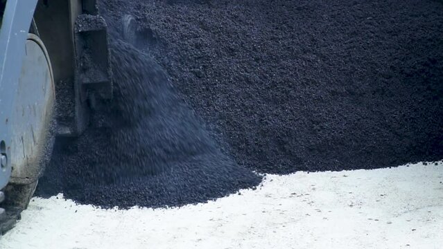 The machine lays a new layer of asphalt, hot asphalt is laid on a new road, road repair, slow motion