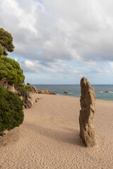 Paisaje marino de la costa brava con la imagen de la playa con grandes rocas en la arena y verdes...
