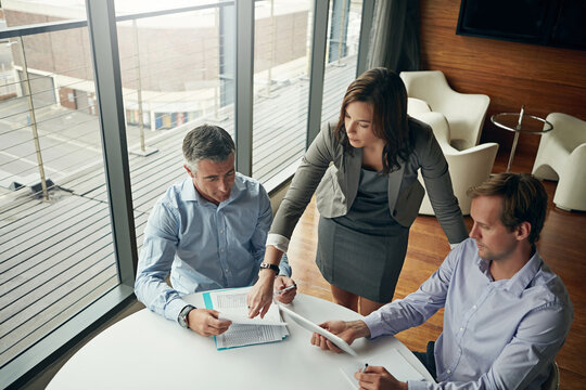 Top view, business people and meeting for trading, tablet and financial planning in workplace. Corporate, men and woman brainstorming, device and paperwork for investment, traders and modern office