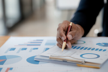 Business man pointing to a pie chart document showing company financial information, He sits in her private office, a document showing company financial information in chart form. Financial concepts
