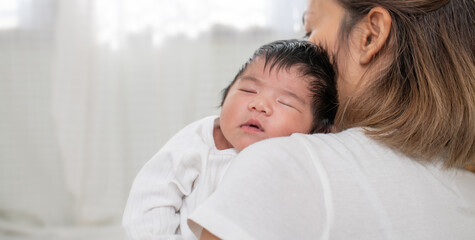 happy loving family. mother playing with her baby hugging in the bedroom , portrait of asian mother playing with newborn baby, health care family love together. asian girl lifestyle..