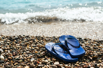 Wet blue rubber flip flops at the pebbly beach