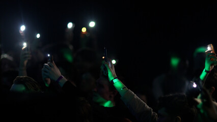 Fans Raise Hands and takes a photos in Front of Bright Colorful Strobing Lights on Stage.