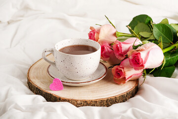 Morning breakfast in bed with cappuccino coffee and pink roses flowers. Holiday greeting card