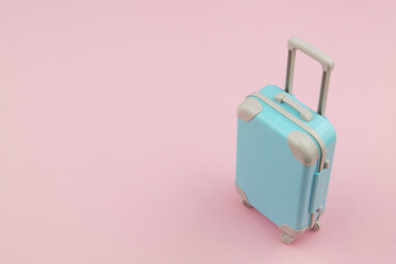 Blue travel suitcase or bag on pink background with copy space for text. Vacation and travel concept.